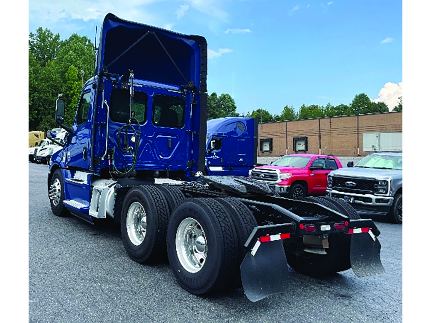 Freightliner Cascadia126 truck chassis with blue cab and dual rear axles, fifth wheel area visible, daycab configuration, rear mud flaps.