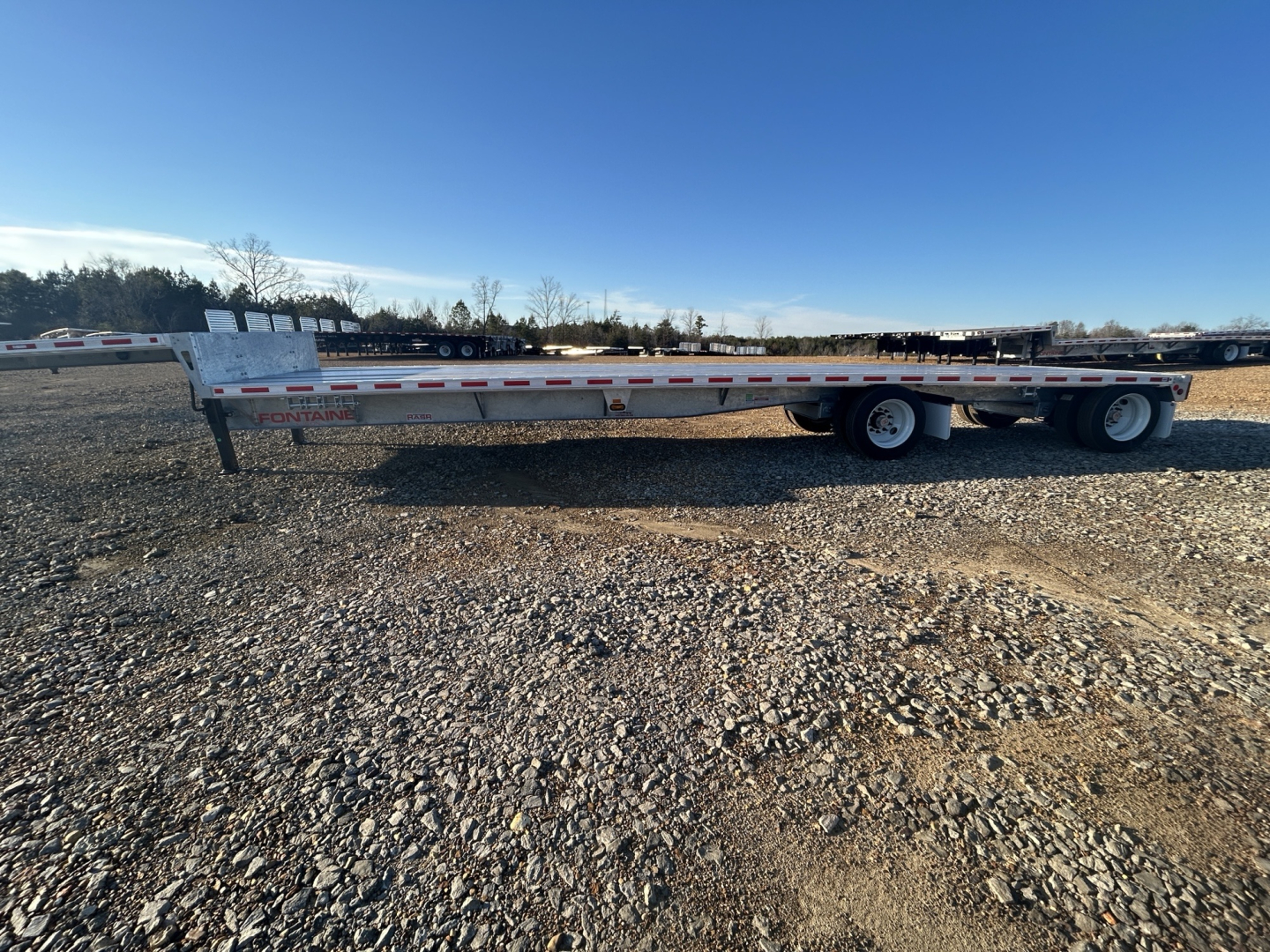 New Fontaine 48' combo drop deck trailer with galvanized frame and wide-spread axle, side view showing dual rear axles and reflective tape.