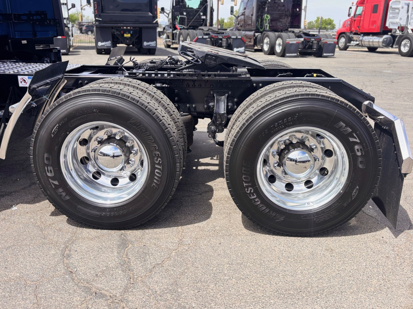 Truck rear dual-axle configuration with big tired Bridgestone tires and chrome wheels. View shows left and right rear wheels, suspension, frame, and mud flaps.