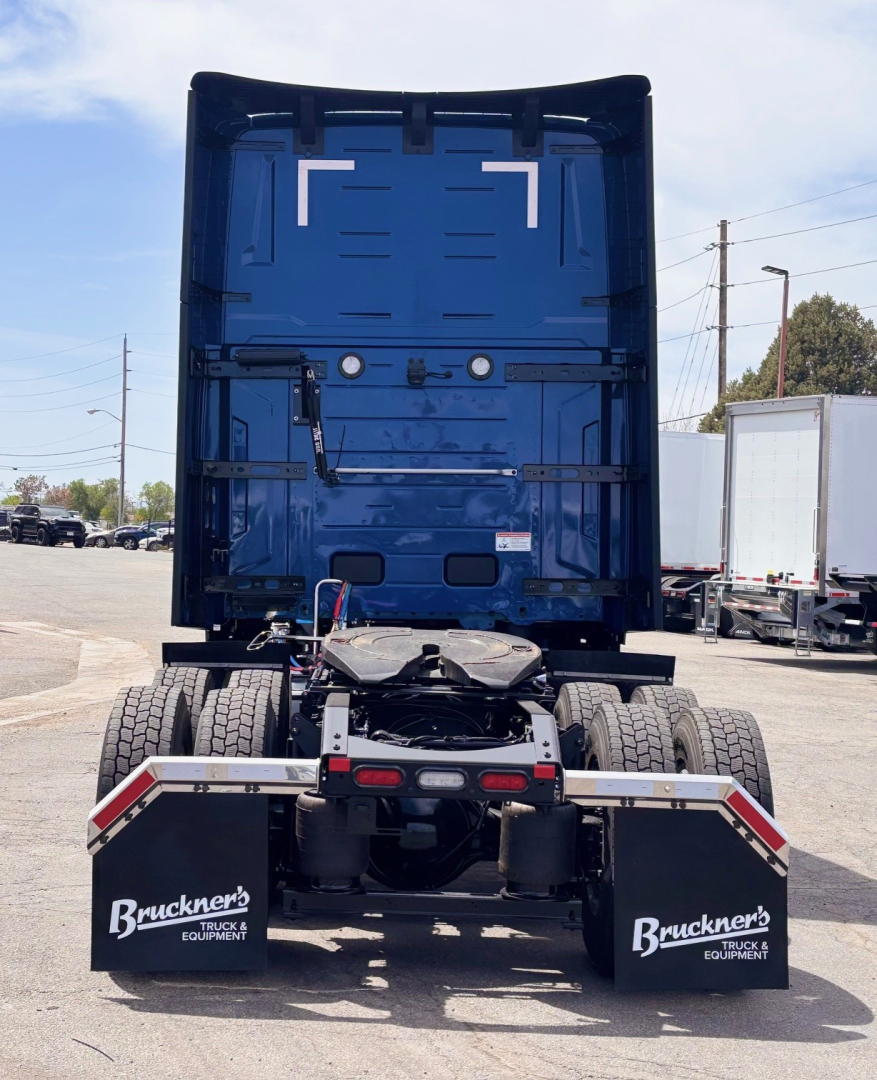 Back view of a blue Mack PR64T76H truck tractor showing rear chassis, dual rear axles, mud flaps with Bruckner's logo, and fifth wheel housing.