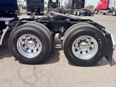 Truck rear dual-axle configuration with big tired Bridgestone tires and chrome wheels. View shows left and right rear wheels, suspension, frame, and mud flaps.