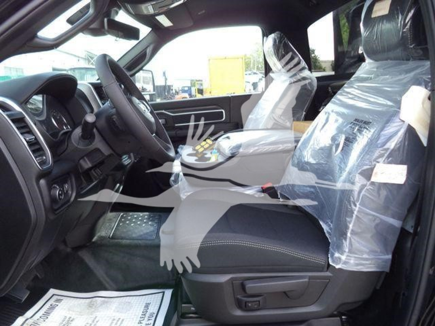 Ram 4500 Big Horn truck interior view showing front seats with protective plastic, steering wheel, and dashboard.