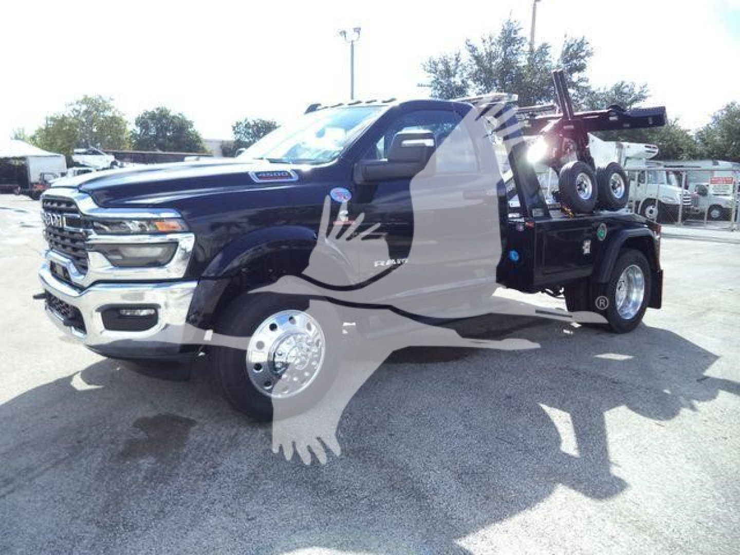 Ram 4500 tow truck with flatbed and hydraulic winch showing front grille and wheel, stock number BIGHORN4500NGS.