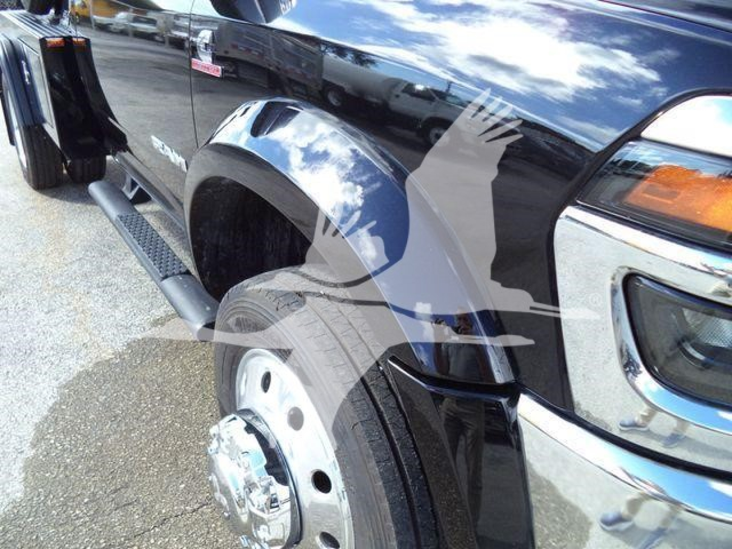 Truck fender and wheel of a new 2026 Ram 4500 Big Horn with side steps and chrome trim; reflections on black paint.
