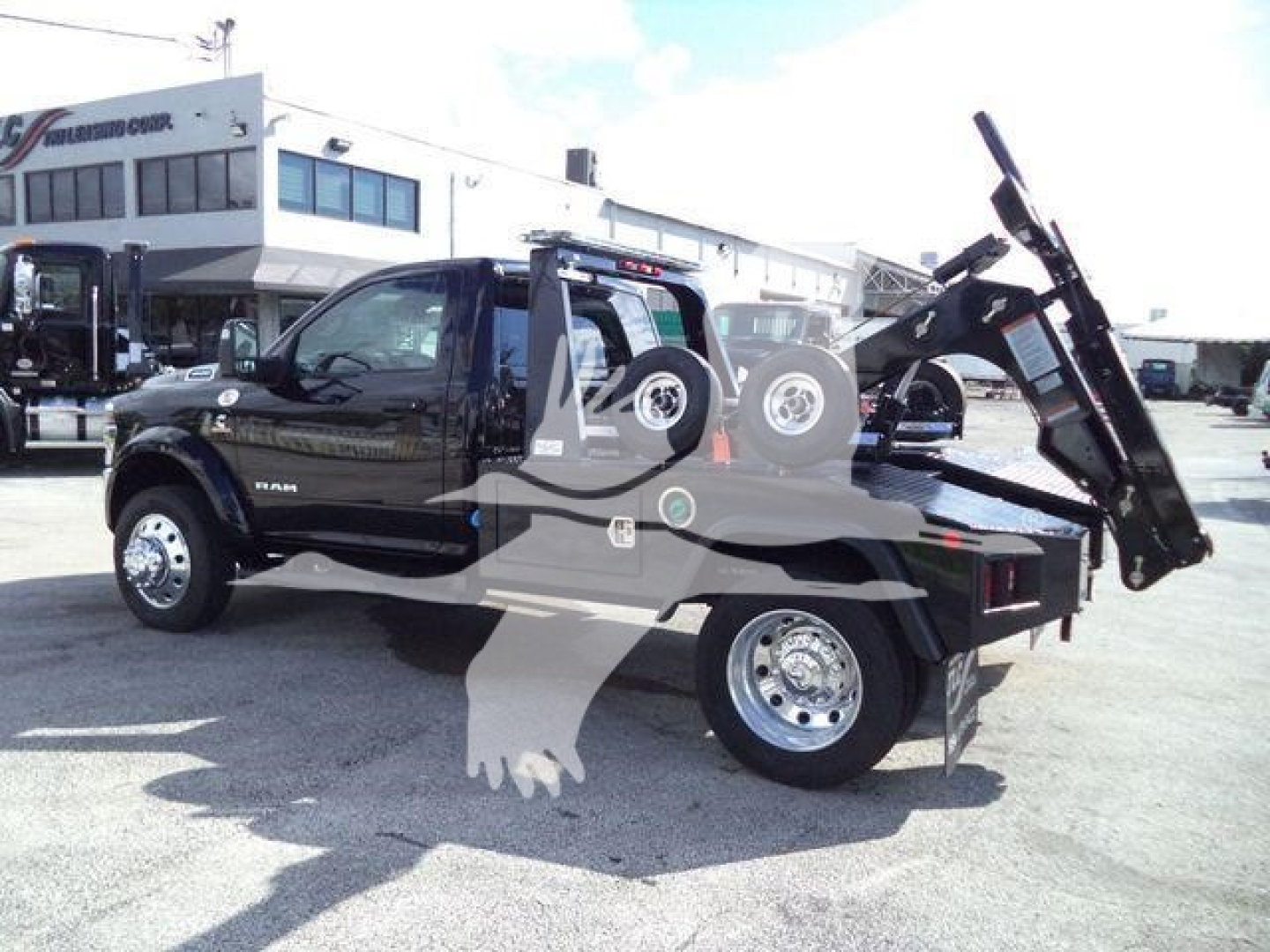 Ram 4500 Big Horn pickup truck with a mounted hydraulic dump bed and spare tire on the rear, side view showing towing/winching equipment and large chrome wheels.