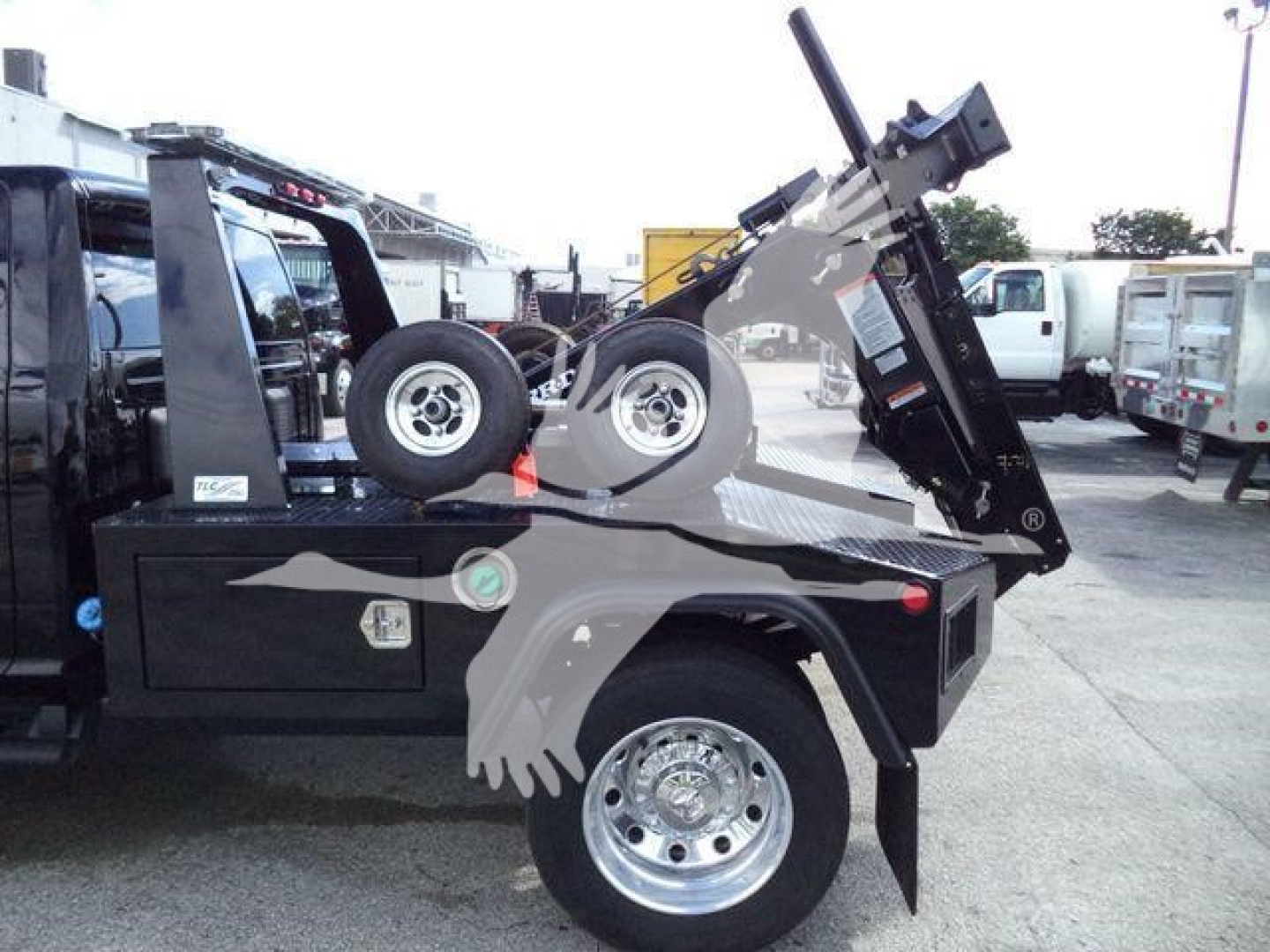 Truck bed with mounted winch system on Ram 4500 Big Horn showing heavy equipment and spare wheel; flatbed with tilt mechanism and hydraulic winch assembly visible.