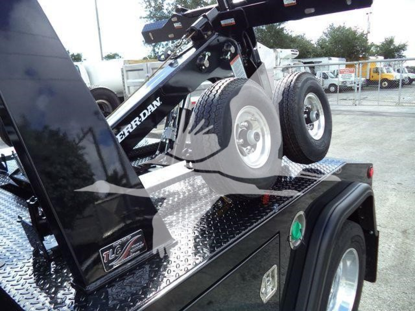 Ram 4500 Big Horn winch truck on a trailer bed with diamond plate surface and spare tire mounted, visible hydraulic lift and rear wheel fender.
