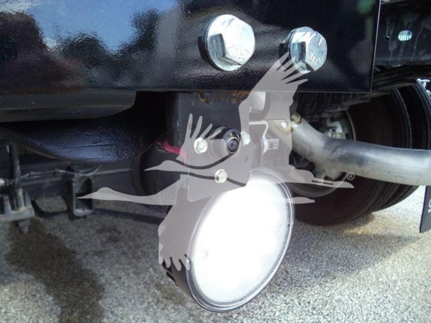 Ram 4500 winch setup with round LED light and hitch bolts visible under truck frame; winch housing and hydraulic line visible.
