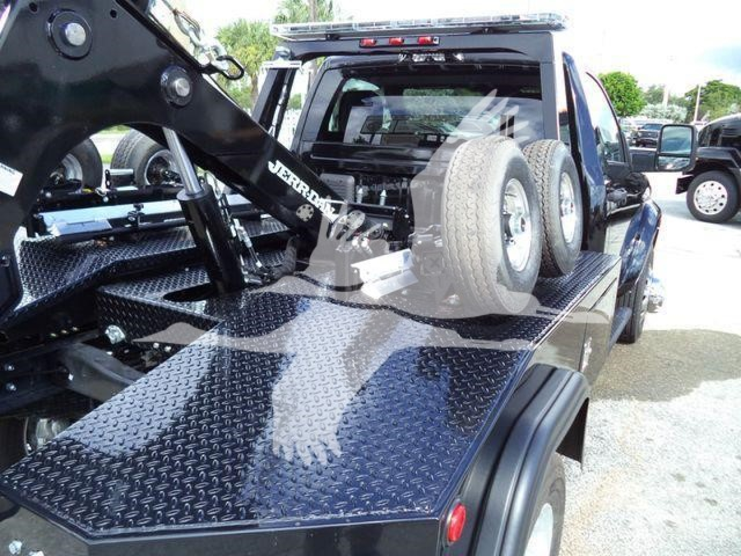 Truck bed with heavy-duty flatbed and mounted winch system, Ram 4500 style chassis, spare tires mounted on cab rear, diamond plate surface, towing equipment visible.