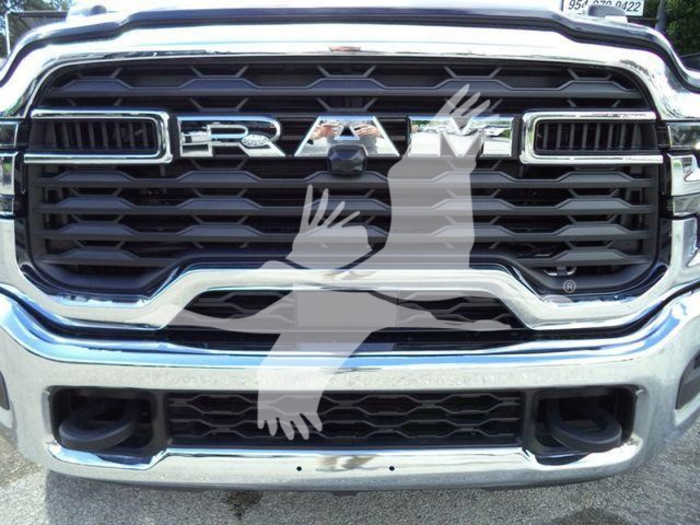 Ram front grille badge text RAM with chrome surround, close-up view of the vehicle front showing grille and bumper.