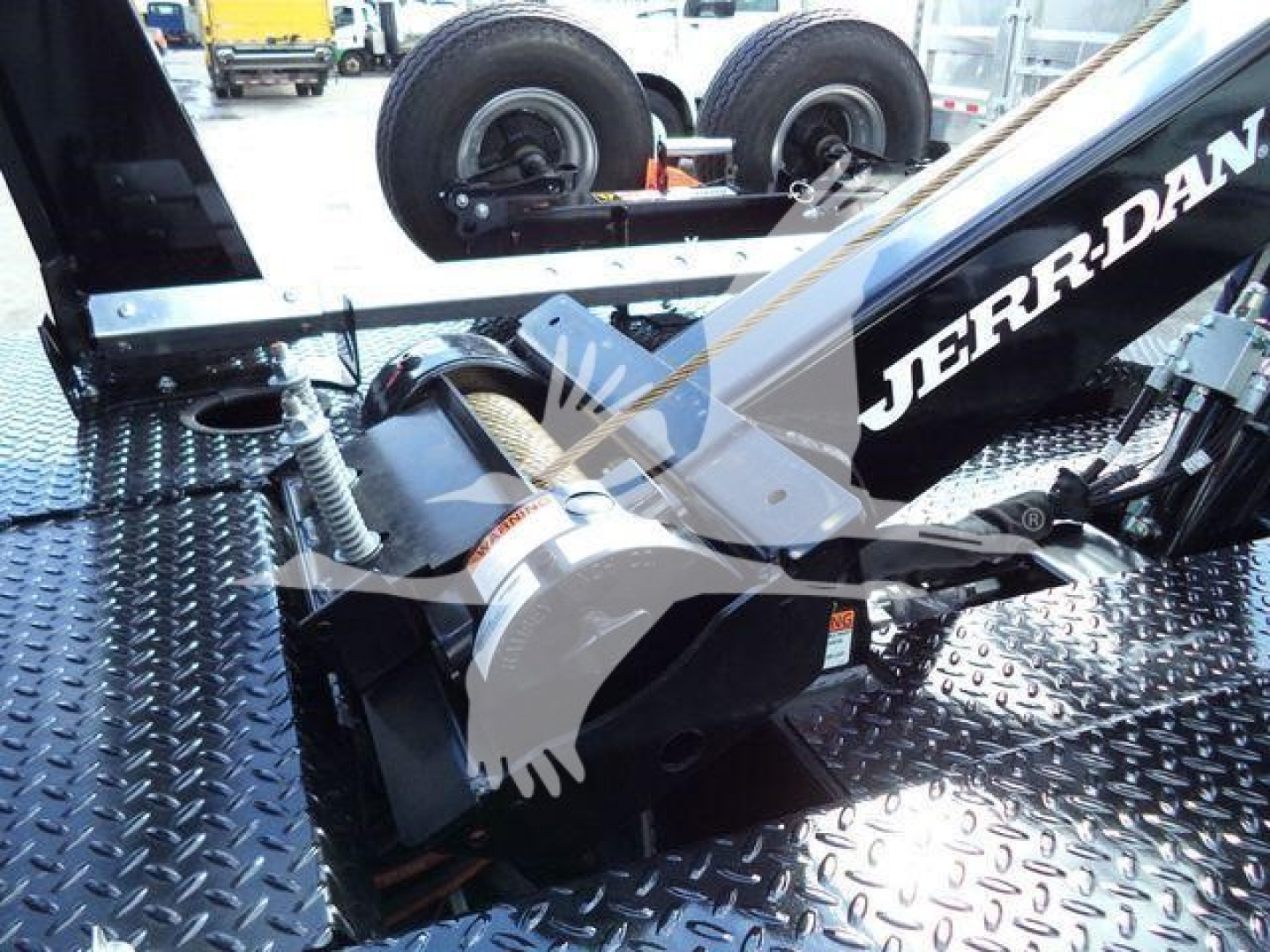 Winch assembly on flatbed with labeled hydraulic motor and hook block, Ram 4500 truck component, tires in background.