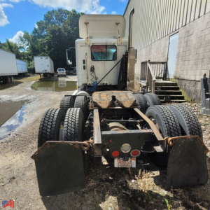 Truck chassis rear view showing dual rear axles and mounting brackets; visible license plate with 9 8 8 3 4; mud flaps; Freightliner Columbia 120 cab in background.