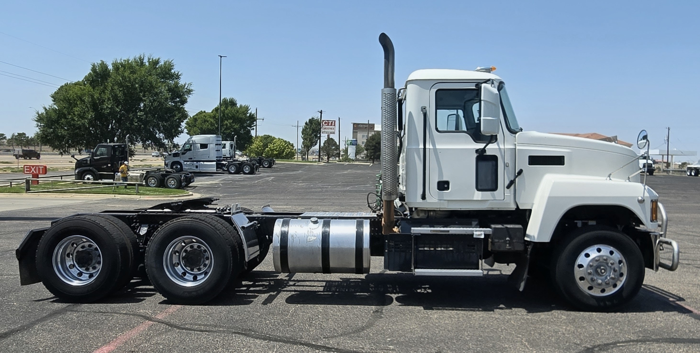 Truck cab and chassis showing Mack PI64T with three rear axles and fuel tanks, side exhaust stack visible