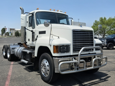 Mack PI64T conventional daycab truck in white, front three-quarter view, with grille guard and dual rear axles visible.