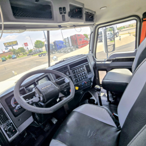 Mack PI64T truck cabin interior showing steering wheel, dashboard with gauges, center console, and driver seat.