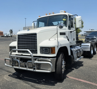 Truck front view of a 2020 Mack PI64T conventional daycab showing large chrome grille, bumper guard, dual exhaust, and front wheels.