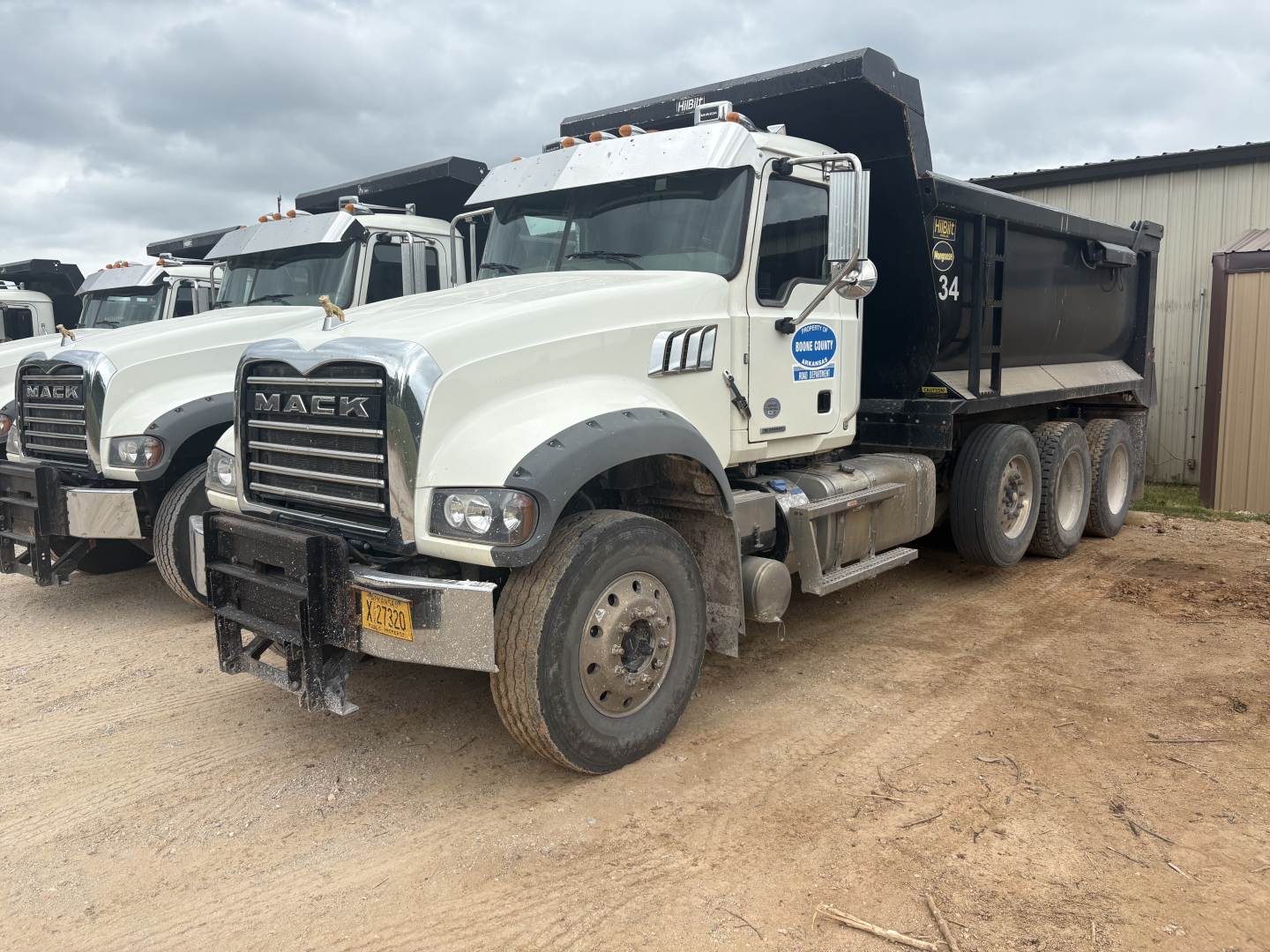 Mack GR84F dump truck in service showing grille, front bumper with license plate, dual rear wheels, and black dump bed.