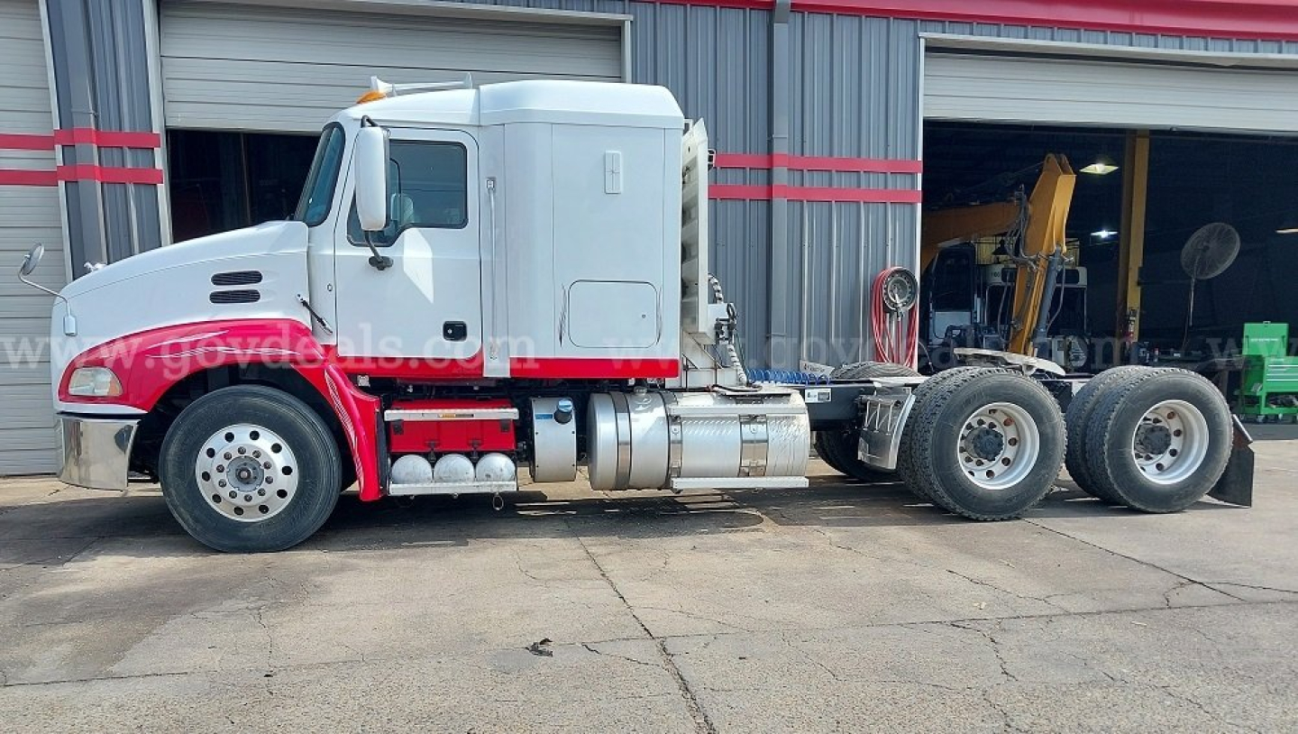 Mack Pinnacle cab and chassis truck side view showing white cab with red lower section and dual rear axles.