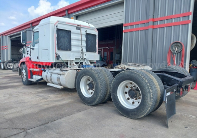 2014 Mack Pinnacle cab and chassis tractor in service, side view showing dual rear axles with dual tires, fuel tanks along the frame, red and white color scheme, and a large exhaust stack.