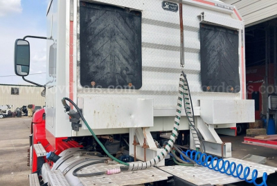 Rear view of a 2014 Mack Pinnacle cab and chassis showing dual rear doors, rear bumper area, and external hoses/coiled air lines.