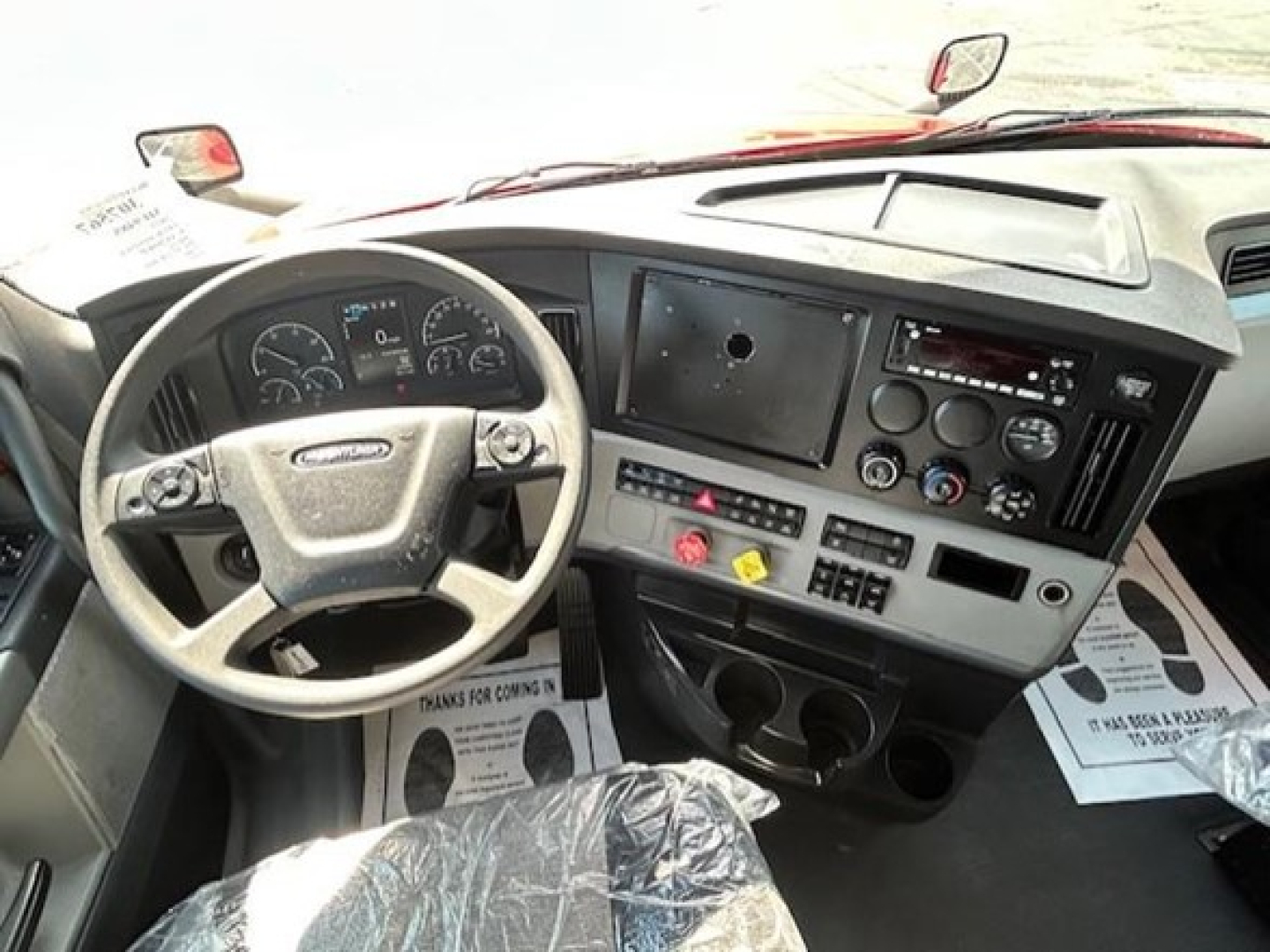 Freightliner Cascadia 126 cab interior showing steering wheel and dashboard controls with center console and gauges.