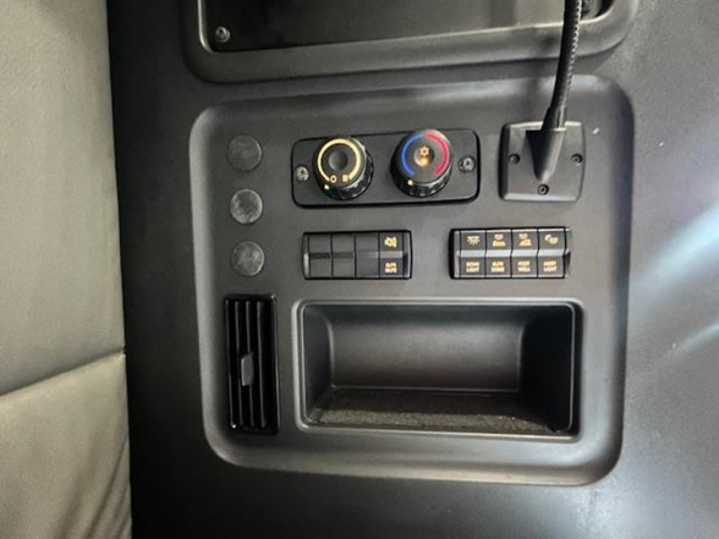 Truck dash area with two circular climate knobs, small control panel, USB/connector slot, and empty storage pocket.