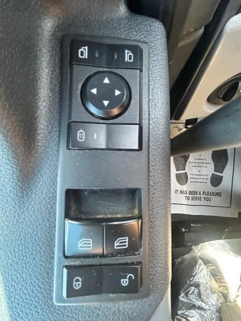 Truck interior control panel with window and mirror adjustment buttons visible on the driver door in a Freightliner Cascadia.