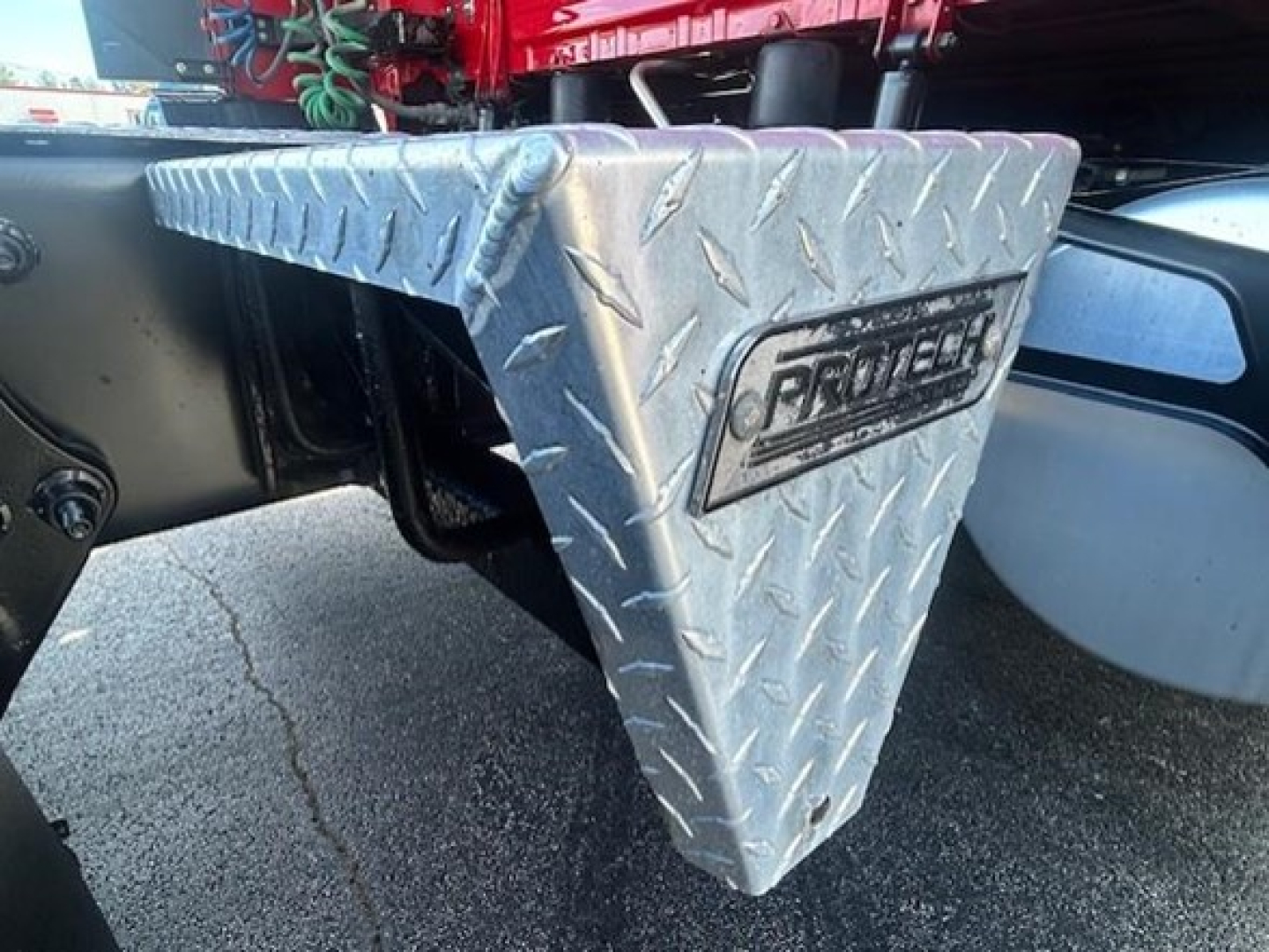 Truck access step with diamond plate ProTech step label visible under Freightliner Cascadia 126, metal texture and undercarriage components.