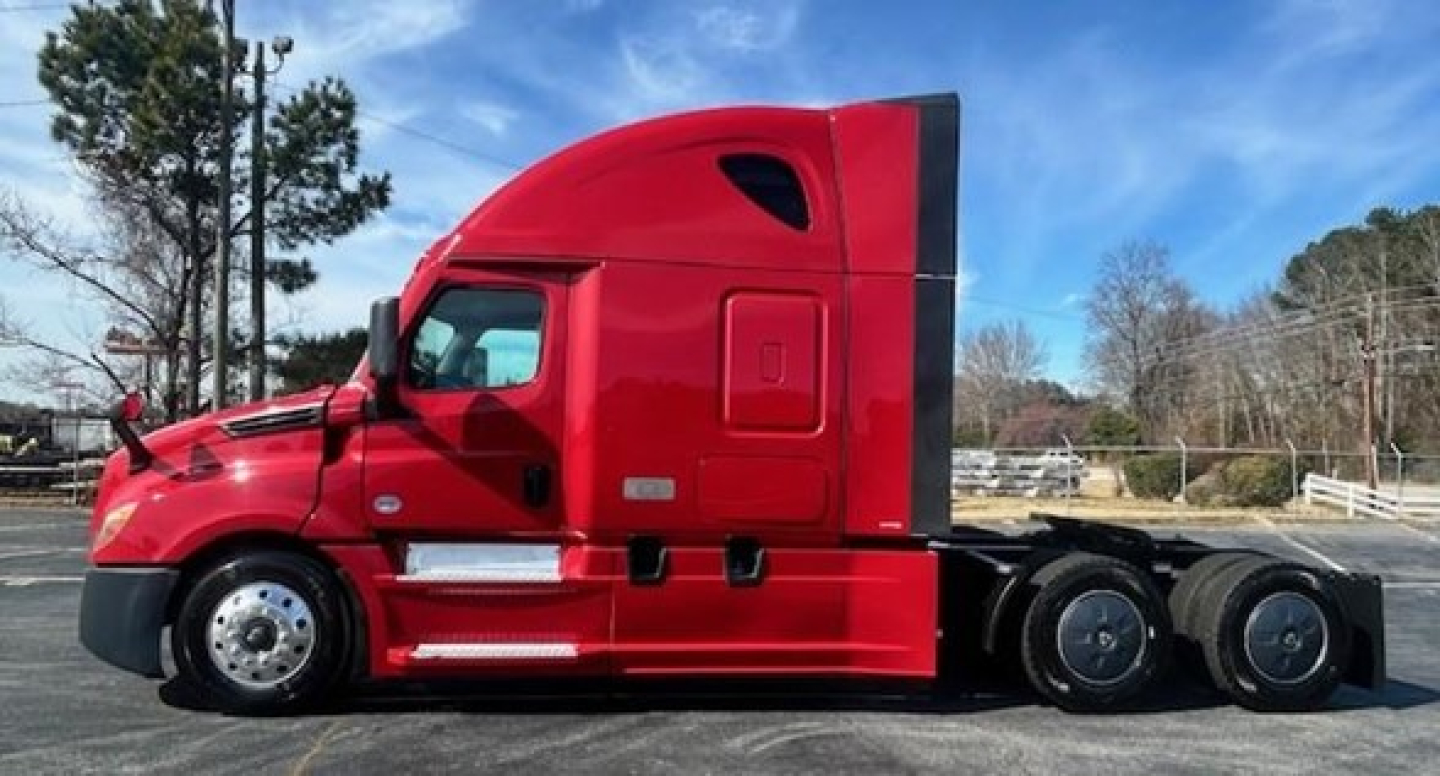Truck side view showing a red Freightliner Cascadia 126 sleeper cab tractor with multiple rear axles.