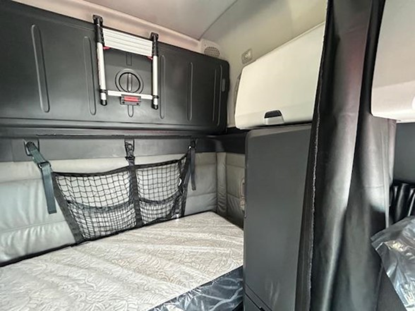Freightliner Cascadia 126 trucks interior sleeper berth area with storage cabinets and mesh net, cabin upholstery visible