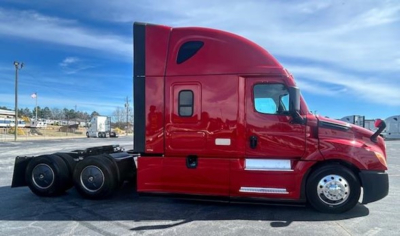 Freightliner Cascadia 126 sleeper tractor in red, side view showing cab and rear chassis with dual rear axles.