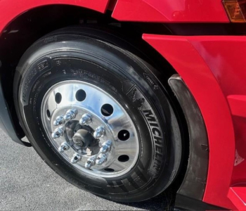 Wheel assembly of a Freightliner Cascadia 126 truck showing a Michelin tire with polished steel rim and lug nuts.