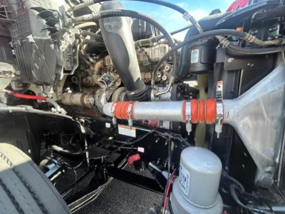 Engine bay of a 2022 Freightliner Cascadia 126 conventional sleeper showing various hoses, pipes, and a grey oil/filter canister.