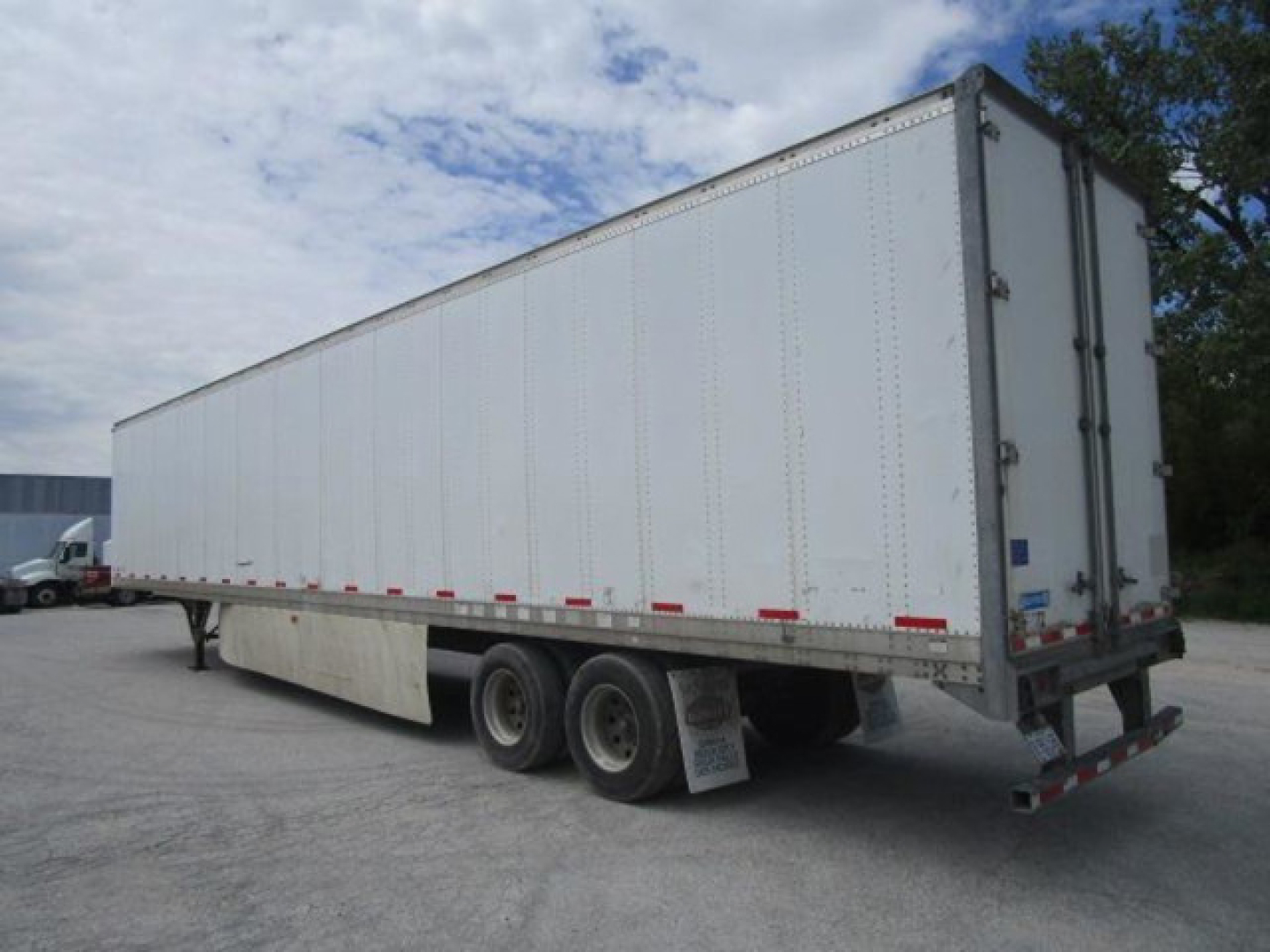 Trailer: 2012 Stoughton van trailer, side view, white, tandem axles, rear doors closed, VIN visible rough trailer body, stock number in photo area.