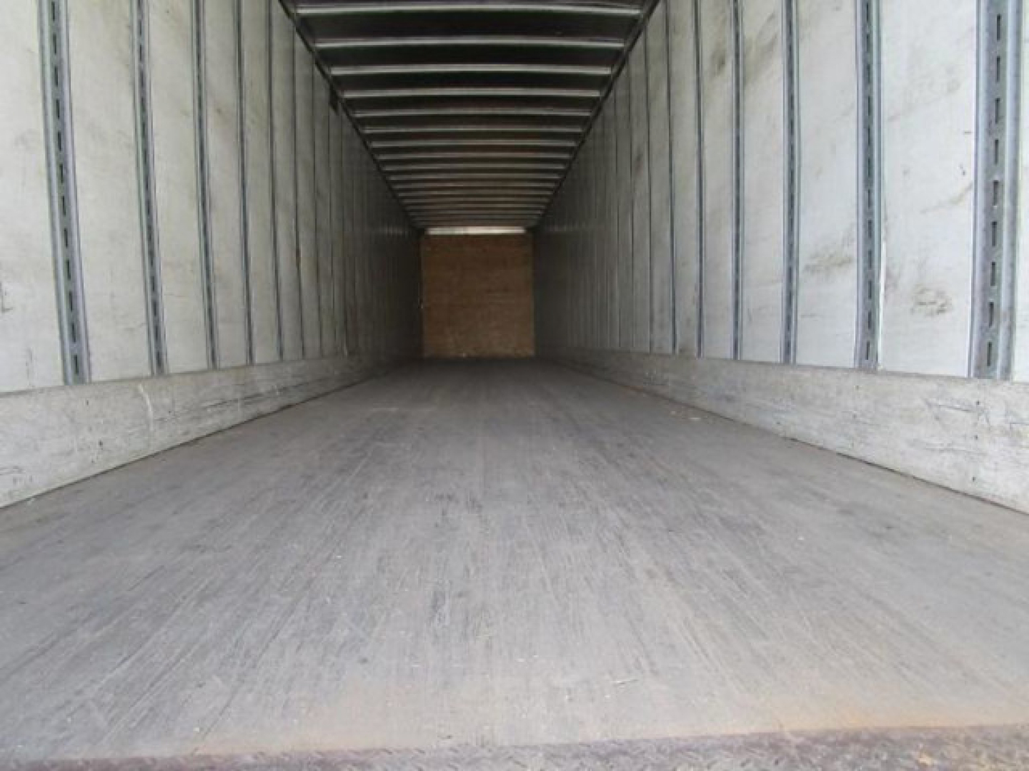 Trailer interior showing empty cargo area with wood bulkhead at far end and metal side walls.