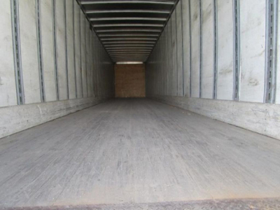 Trailer interior showing empty cargo area with wood bulkhead at far end and metal side walls.