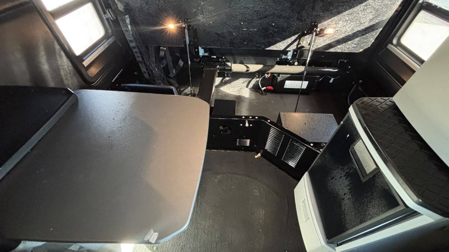 Truck cab interior of a 2022 International LT625 sleeper showing a fold-out table, dashboard area, and storage compartments.