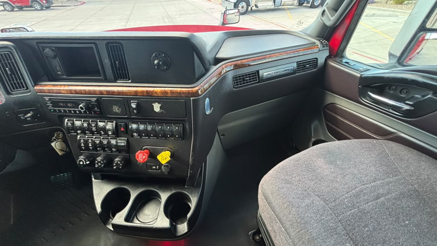 Interior dashboard of a 2022 International LT625 truck showing steering wheel, center console with controls, vents, wood trim, and cup holders.
