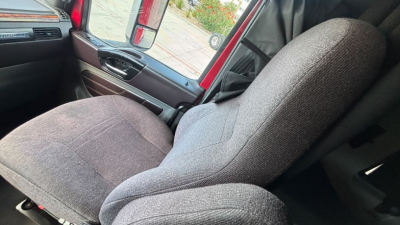 Truck cab interior showing grey fabric seats in a 2022 International LT625, front passenger and driver seats with door panel and window visible.