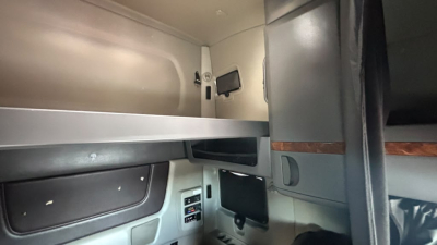 Interior of a truck cab with upper bunk and side paneling; small electronics panel and a recessed shelf visible.