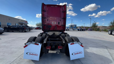 Truck chassis back view showing fifth wheel, rear fenders with MHC mudflaps, and dual rear tires under a red sleeper cabin.