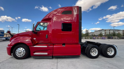 Truck cab side profile showing International LT625 sleeper tractor with red paint, two rear axles, glossy finish, windows, and chrome wheel hubs.