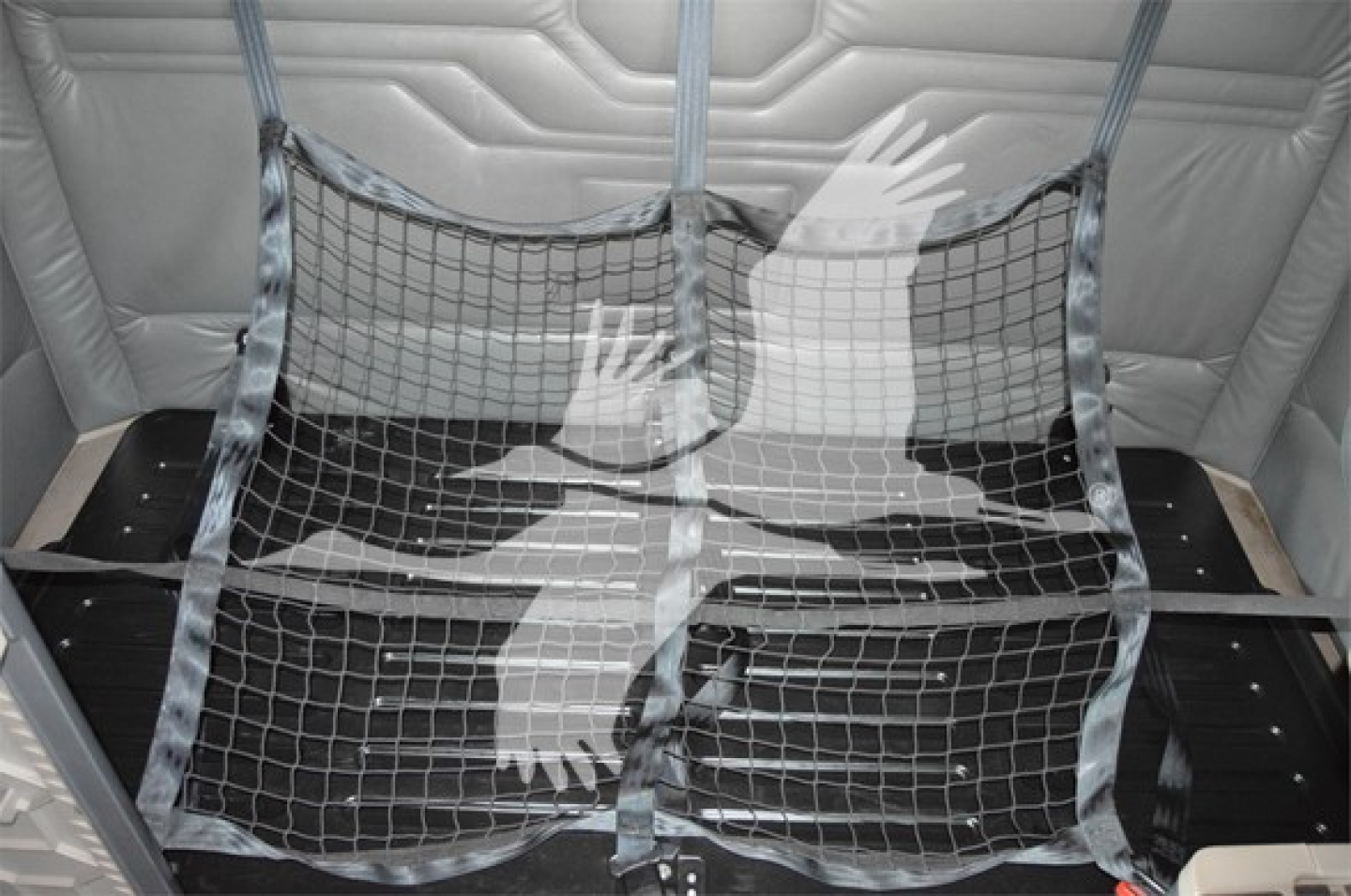 Truck cargo area with metal tie-down nets installed, showing interior padding and a protective divider/grille.