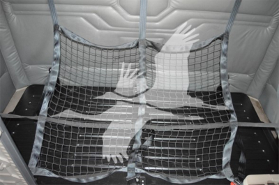 Truck cargo area with metal tie-down nets installed, showing interior padding and a protective divider/grille.