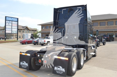 Truck rear view showing 2014 Freightliner Cascadia 125 Evolution with sleeper cab and dual rear axles, black exterior with white graphics