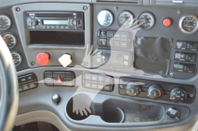 Cab interior of a Freightliner Cascadia dashboard showing gauge cluster, radio, control switches, hazard button, climate controls, and cup holder area.