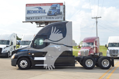 Truck cab with large white dove graphic on black Freightliner Cascadia Evolution 2014 tractor. Billboard sign on top of trailer visible; other trucks in background.