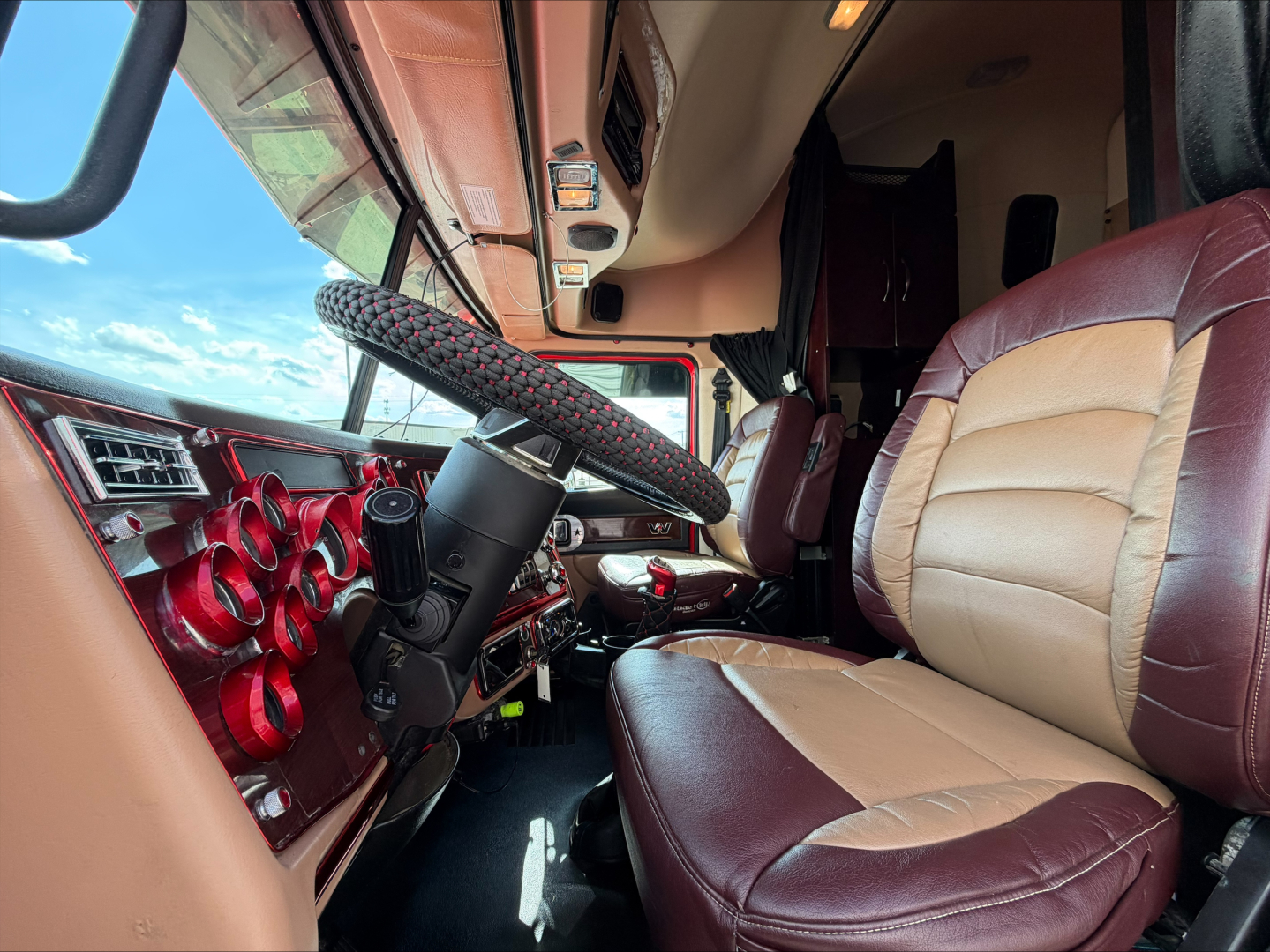 Truck cab interior of a 2020 Western Star 4900 conventional sleeper showing steering wheel, dashboard, and tan-brown seats.