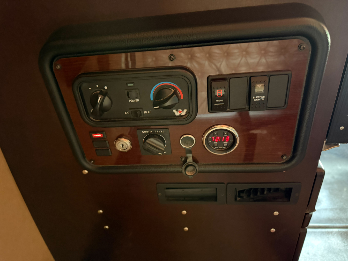 Dashboard panel of a Western Star 4900 showing control switches, gauges, and an ammeter; visible text includes power, level, and speedometer-style gauge.