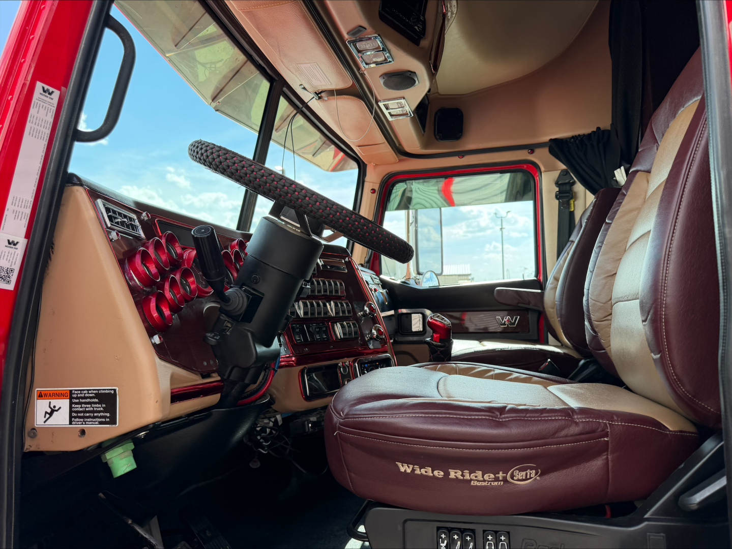 Truck cab interior of a 2020 Western Star 4900 showing brown leather seats, steering wheel, dashboard controls, and window view.